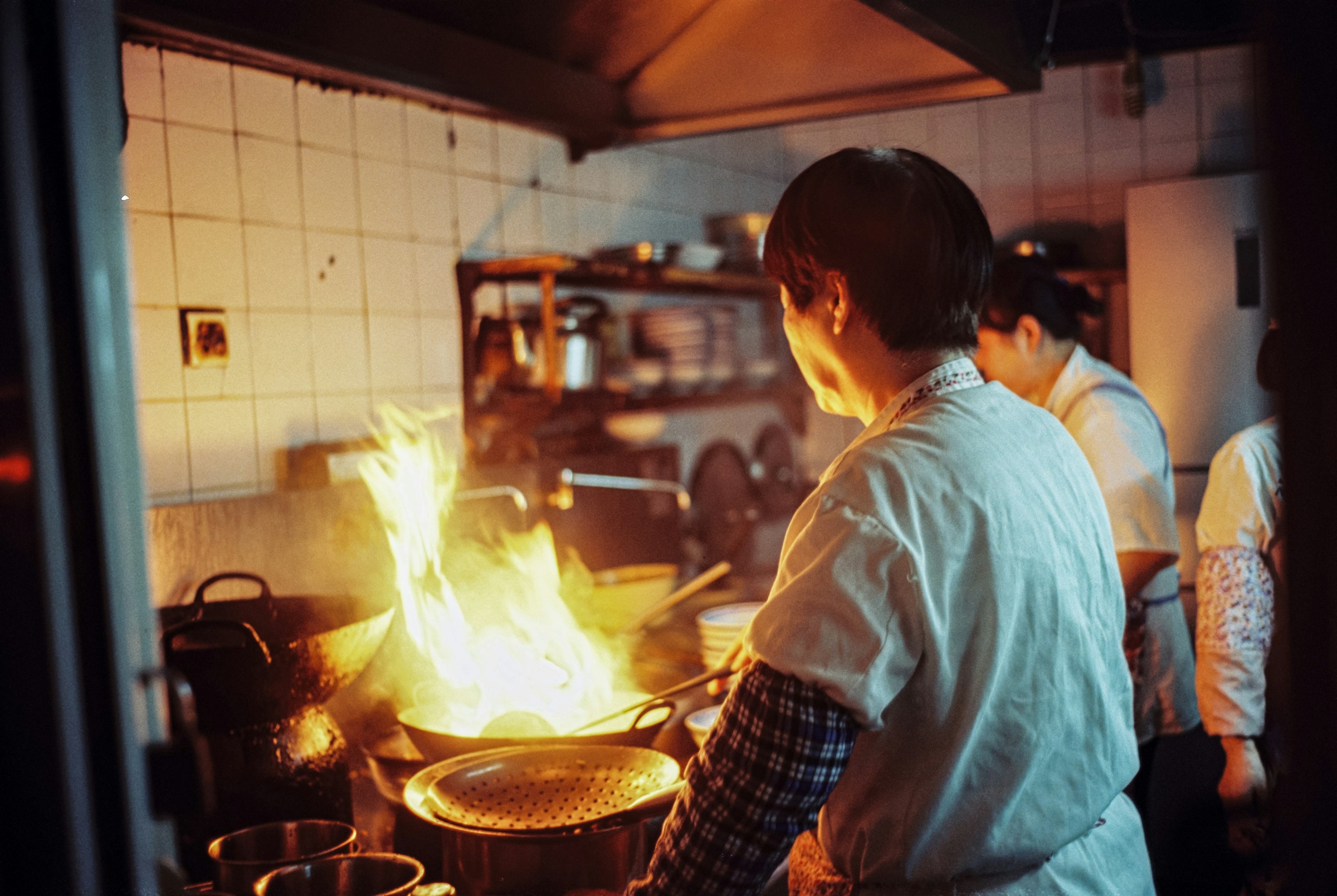Chef cooking over an open flame in the kitchen